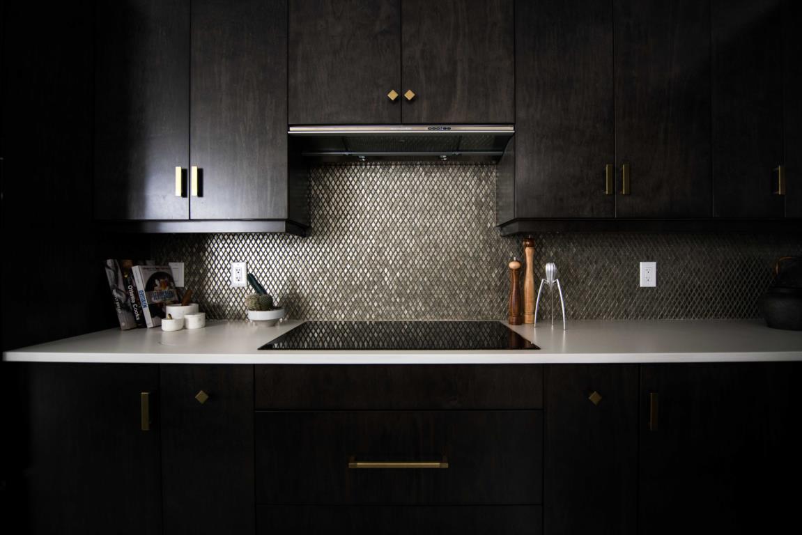 dark, black kitchen cabinets with grey tile backsplash and stove in middle