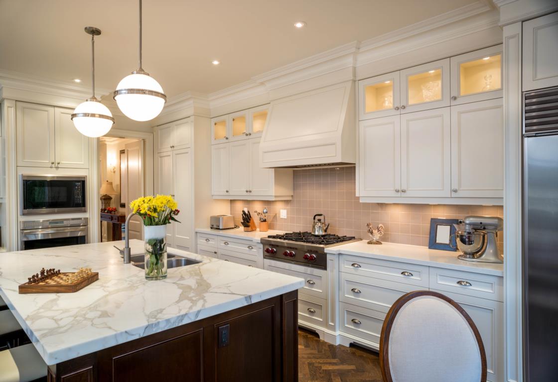 White kitchen with marble countertops, white cabinets and flowers in a vase